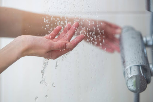 A hand feeling the water from a shower.